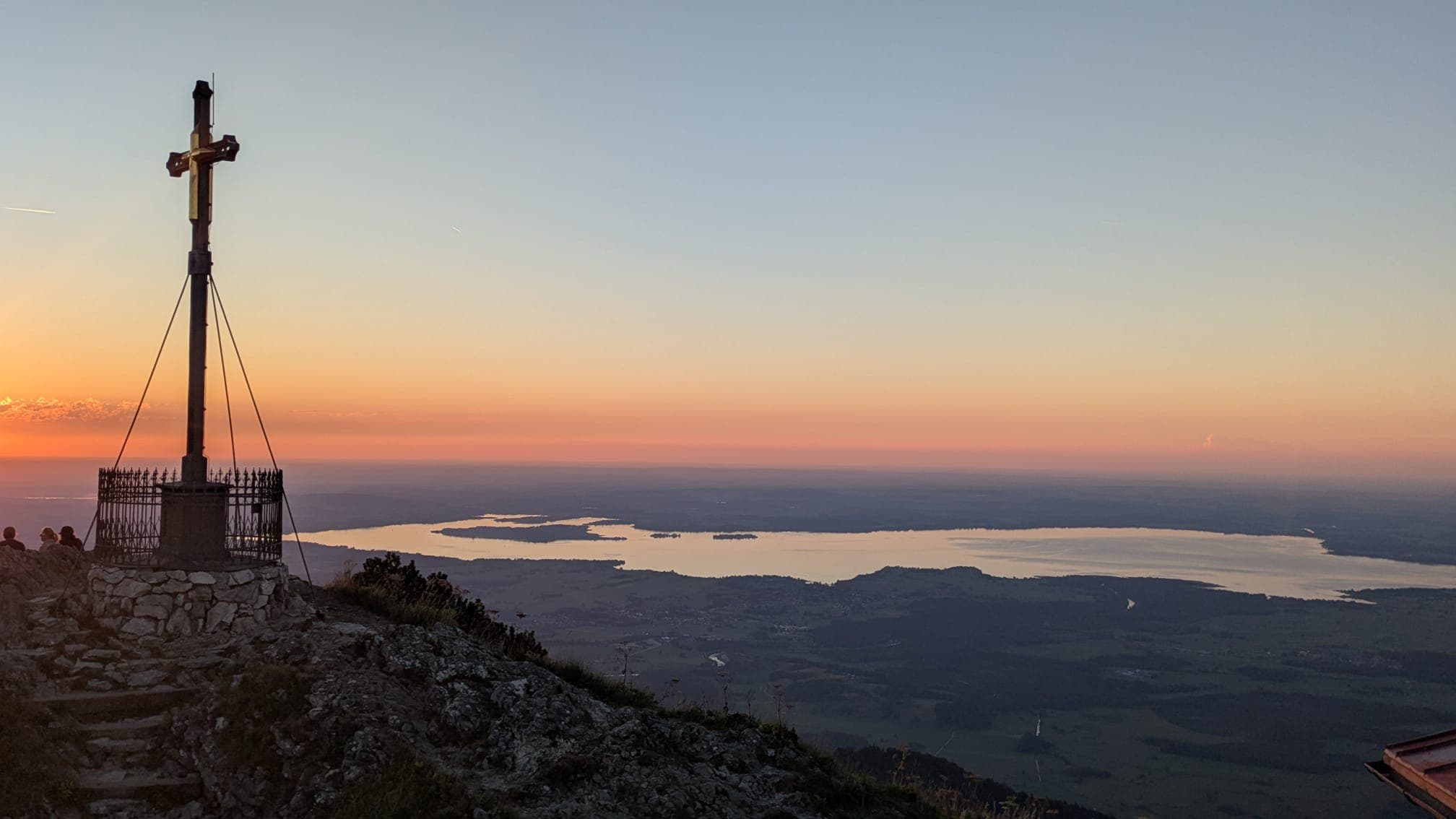 Blick vom Gipfelkreuz des Hochgern über den Chiemsee, kurz nach Sonnenuntergang